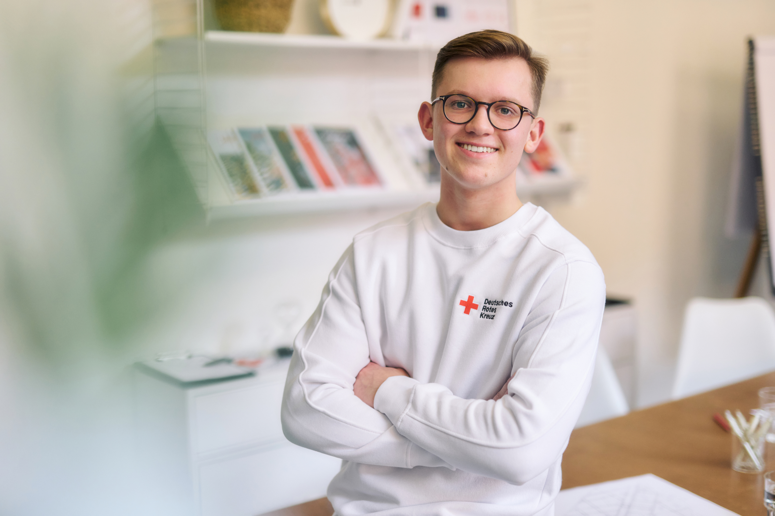 Symbolfoto junger Mitarbeiter des DRK, er trägt ein weißes Sweatshirt 