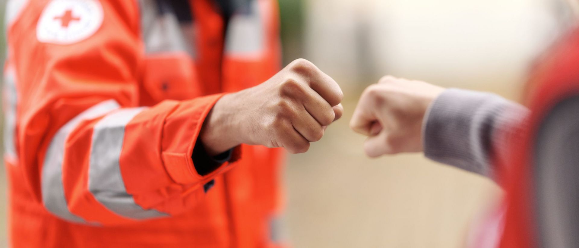 Ehrenamtliche in Einsatzkleidung begrüßen sich mit Faustgruß.