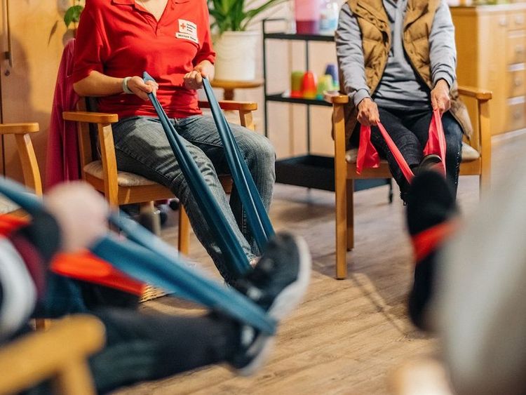 Man sieht eine Sportgruppe, die mit Bändern Bewegung üben.