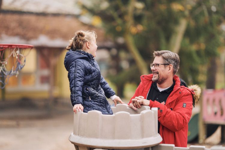 Erzieher und Kind spielen in einer Burg auf dem Spielplatz.