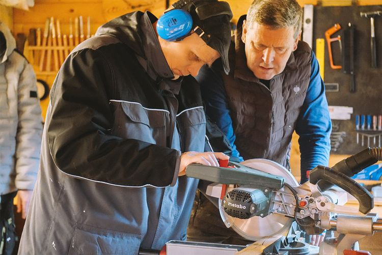 Nutzer erhält Assistenz an der Kappsäge von einer Fachkraft.