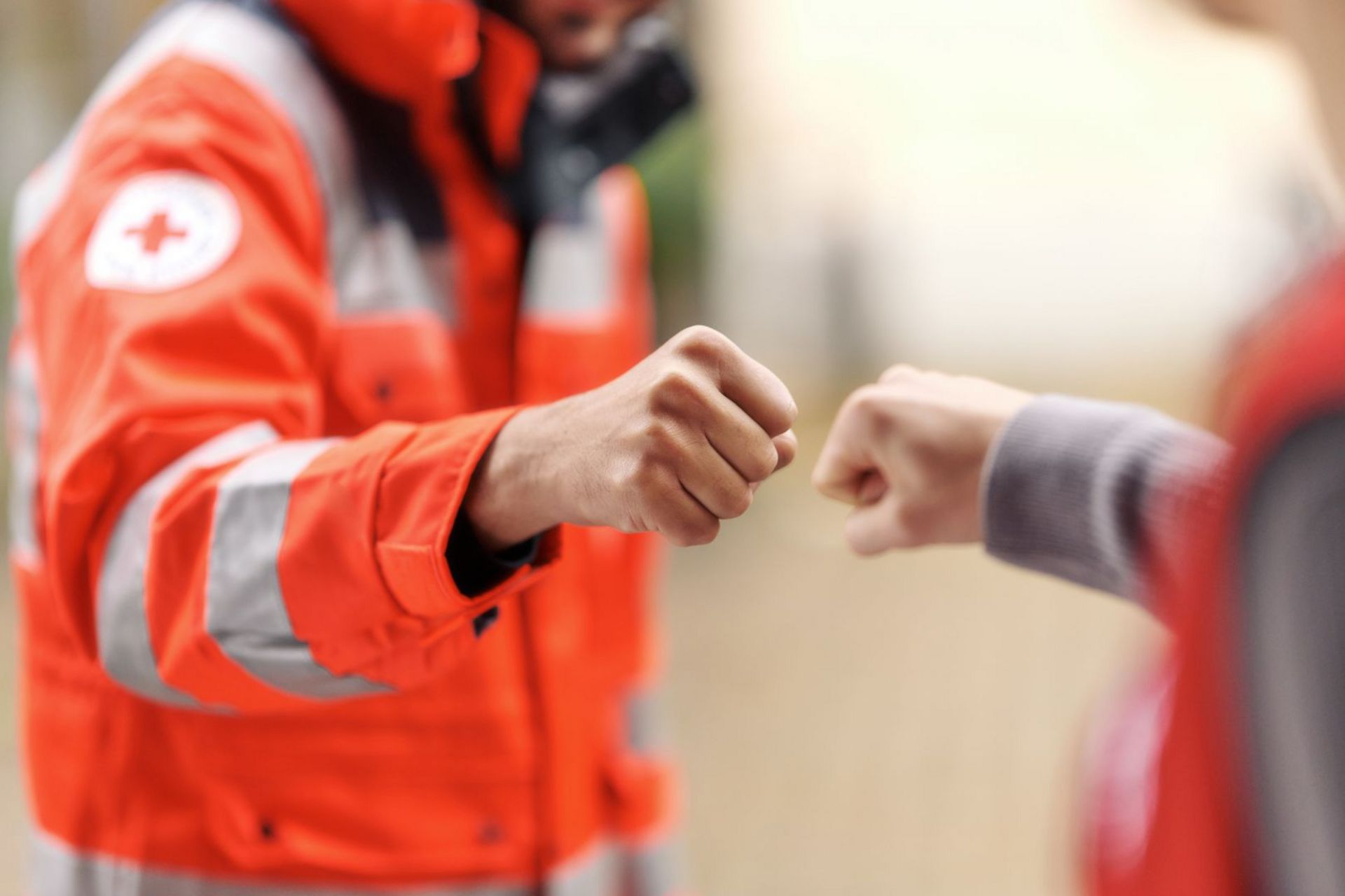Personen in Einsatzkleidung begrüßen sich mit dem Faustgruß.