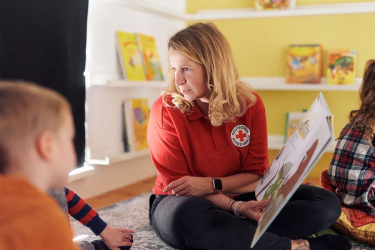 Erzieherin liest Kindern aus einem Buch vor.