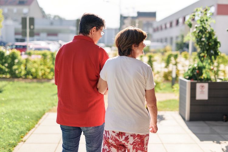 DRK Mitarbeiterin hält Seniorin und beide laufen im Garten.