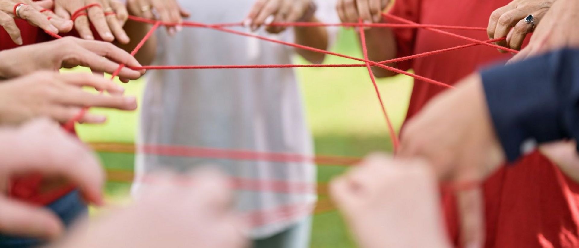 Symbolbild DRK-Mitarbeitenden, welche Fäden in der Hand halten und ein Netz der Verbindung stricken.