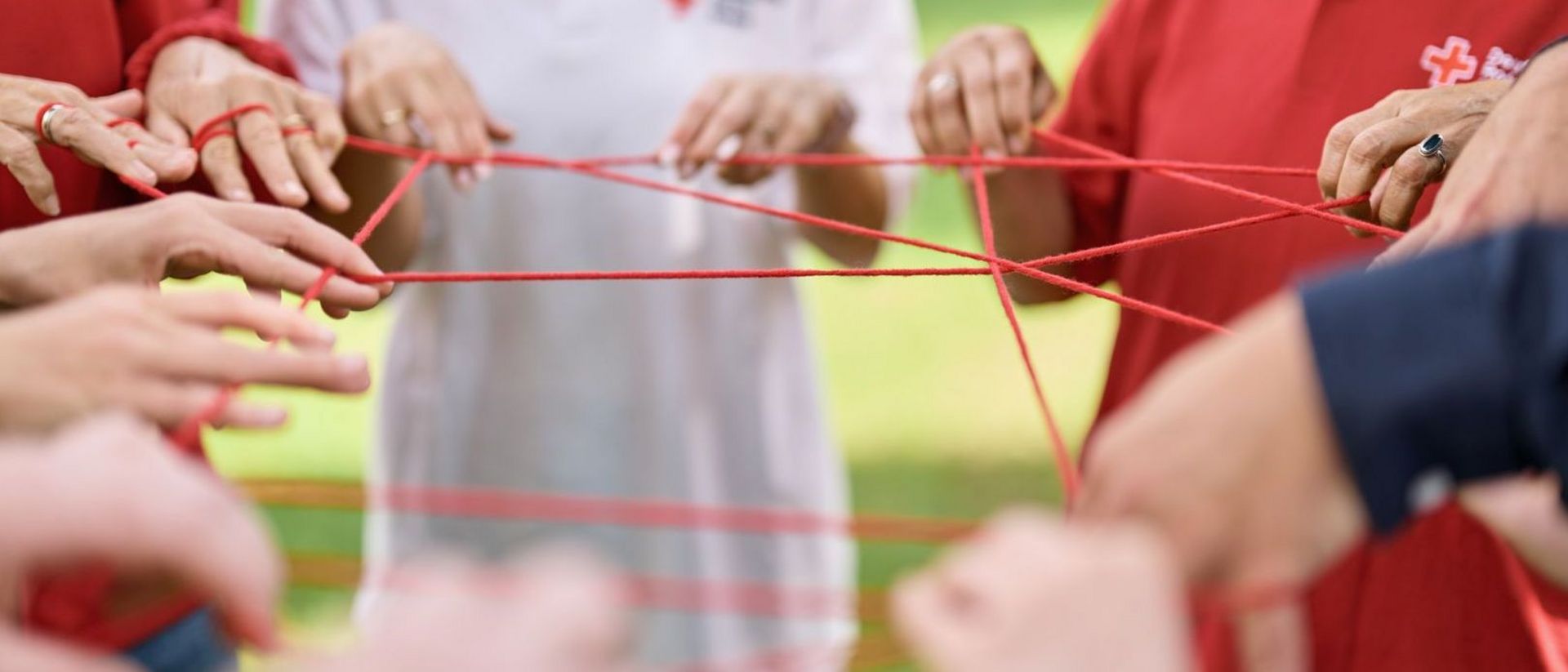 Mitarbeitende halten eine Schnur, die ein Netz darstellt und den symbolischen Chrakter des Zusammenhalts eines Netzes charakterisiert.