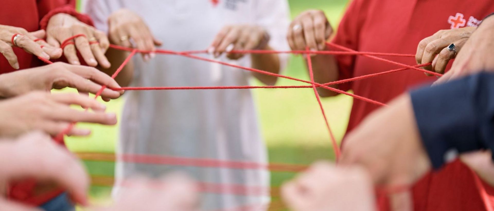 Viele Mitarbeiter des DRK halten eine Schnur, welche wie ein Netz aussieht.