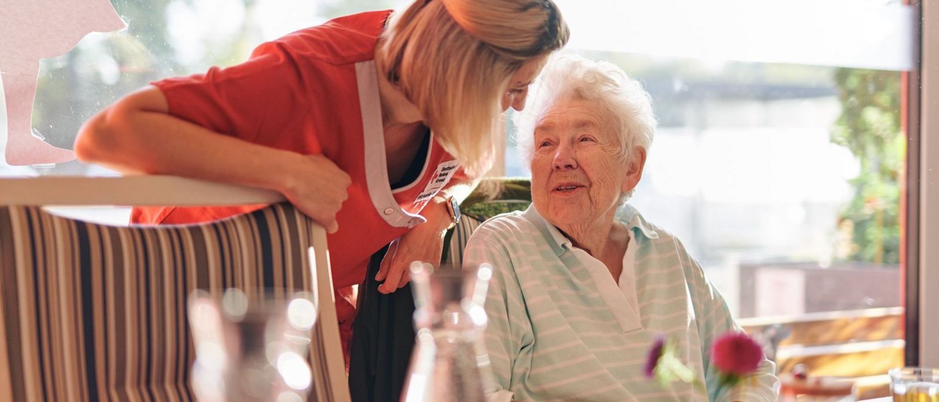 DRK Mitarbeiterin spricht herzlich mit einer Seniorin.