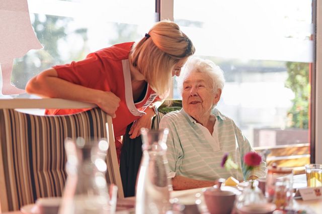 DRK Mitarbeiterin spricht herzlich mit einer Seniorin.