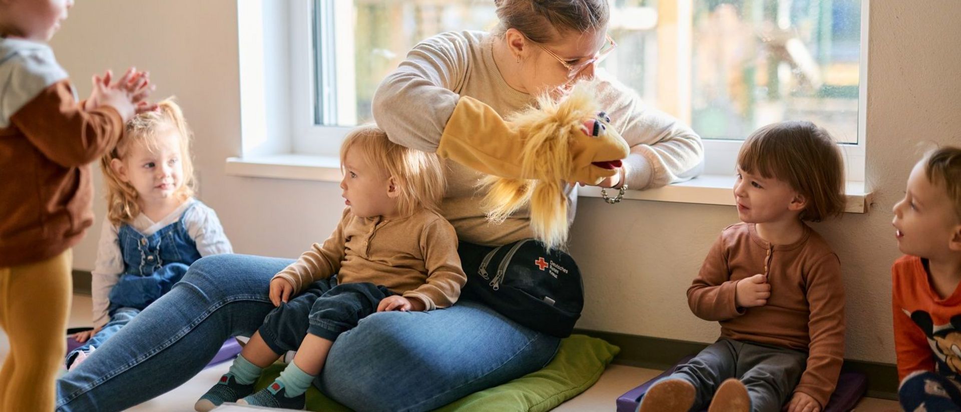 Erzieherin kommuniziert mit Handpuppe zu Kindern.