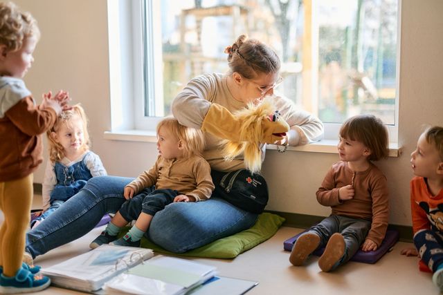 Eine Erzieherin spielt mit einer Handpuppe und unterhält damit die Kinder der Kita.
