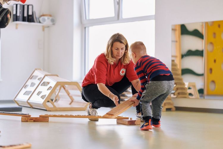 DRK-Mitarbeiterin baut Parcours für ein Kind auf.