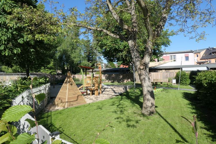 Der Spielplatz bietet natürlichen Schatten durch große Bäume.
