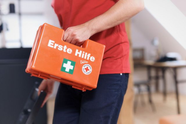 Man sieht eine Hand, welche einen Erste-Hilfe-Koffer trägt.