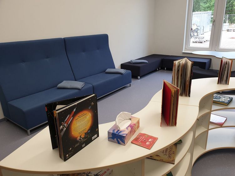 Bücher stehen auf einem Regal vor gemütlichen Sitzgelegenheiten.