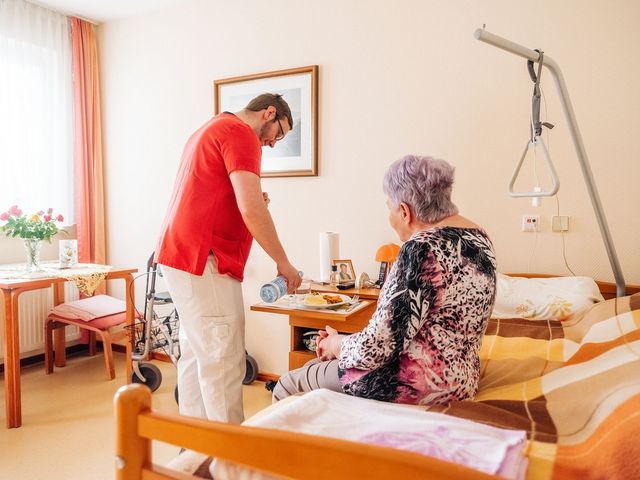 Pflege-Mitarbeiter reicht Bewohnerin die Mittagsmahlzeit.