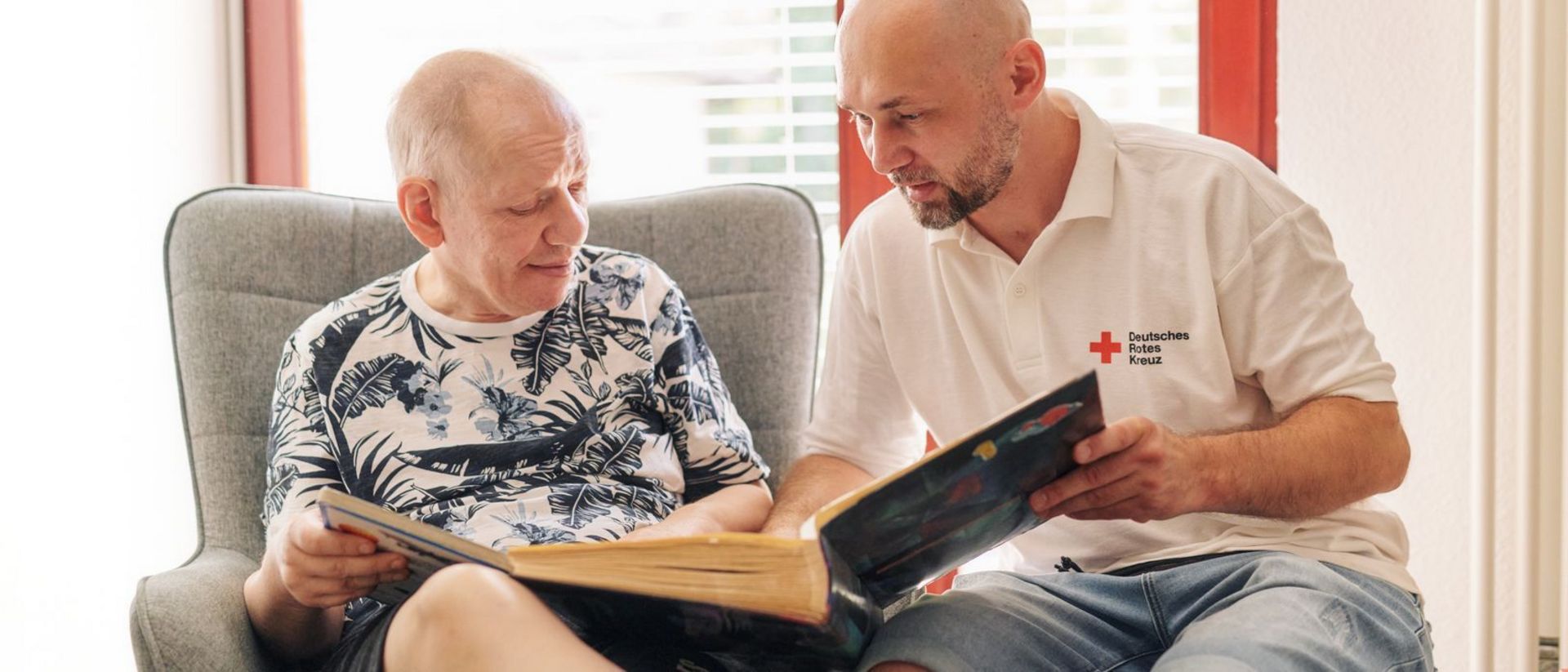 Mitarbeiter liest mit Nutzer ein Buch.