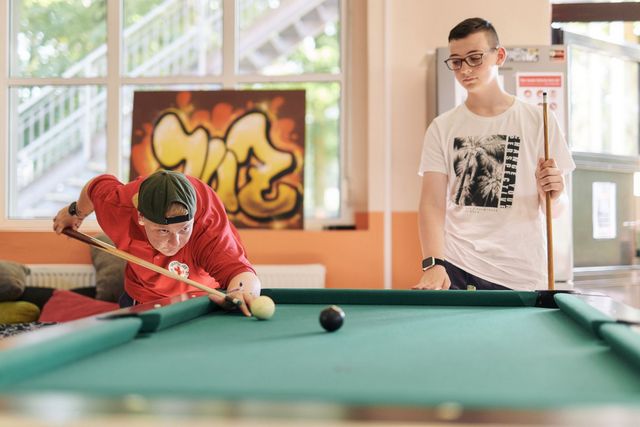 DRK Mitarbeiter und Jugendlicher spielen gemeinsam Billard.
