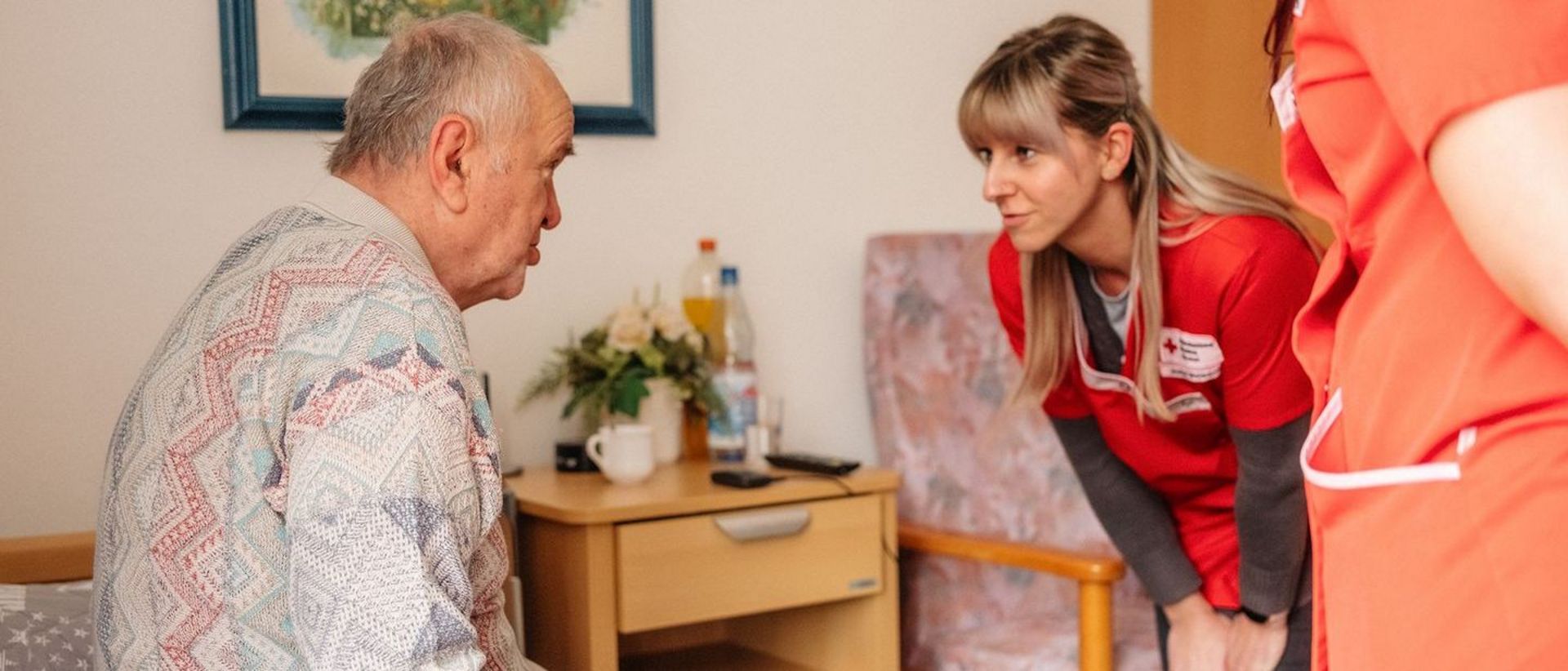 Mitarbeiterin spricht mit Senior auf Augenhöhe.