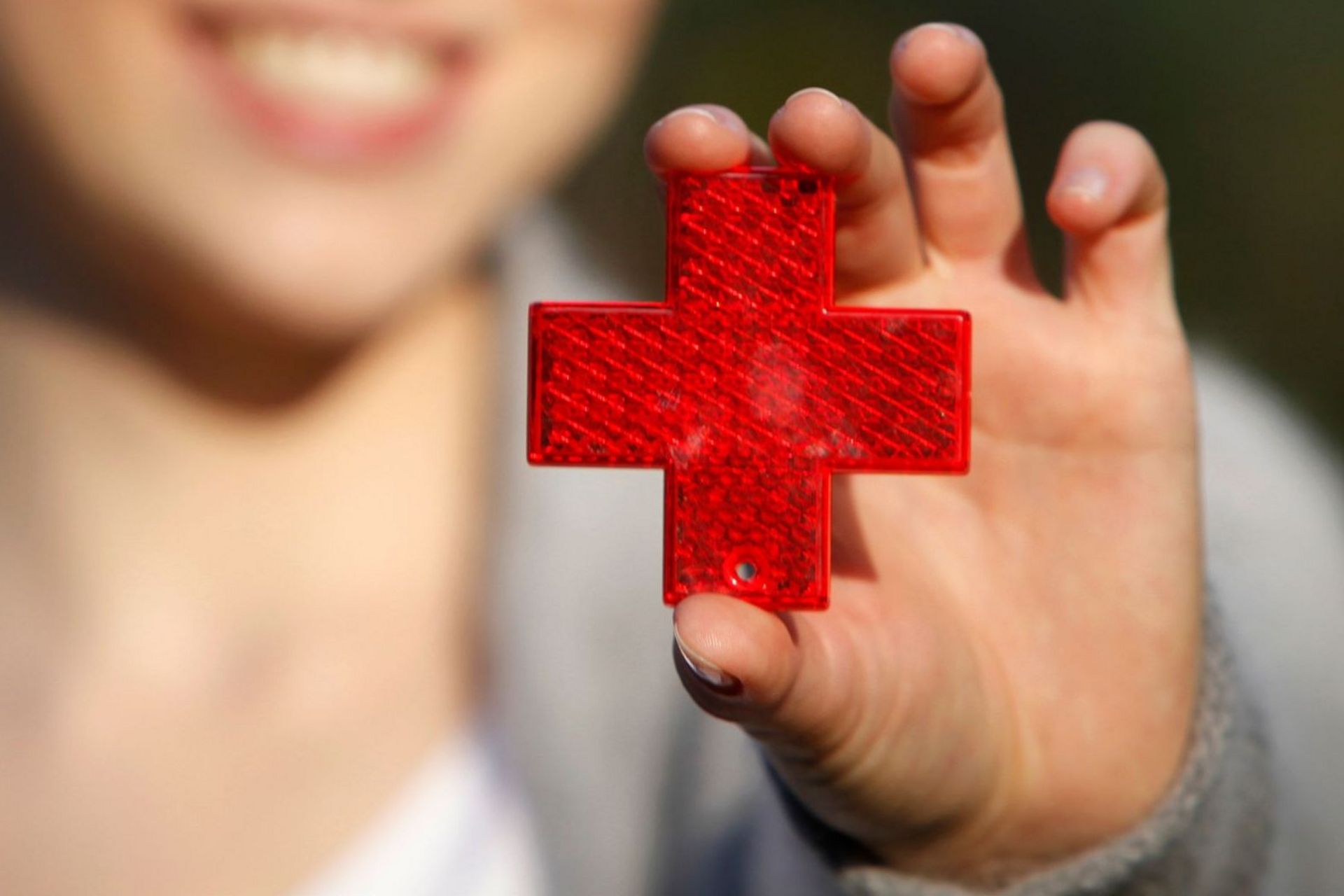 Eine Frau hält das Symbol des DRK in die Kamera.