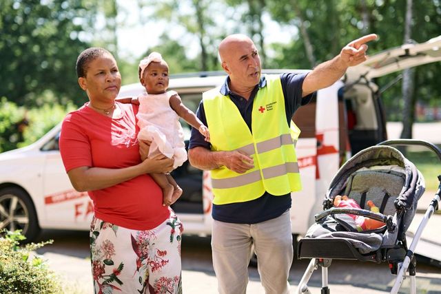 DRK Mitarbeiter weist Geflüchteten den Weg.