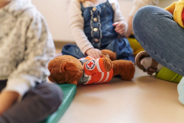Ein Kind spielt mit einem DRK-Teddy.