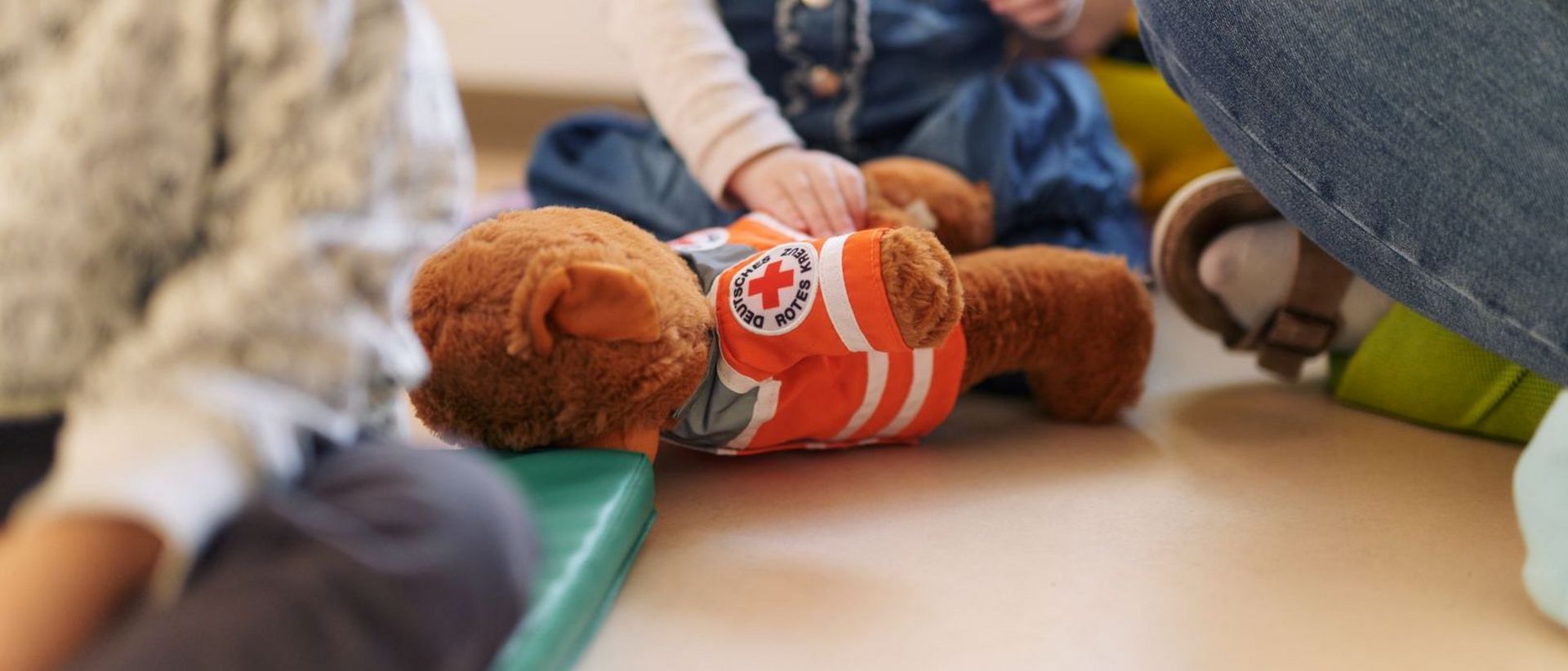Ein Kind spielt mit einem DRK-Teddy.