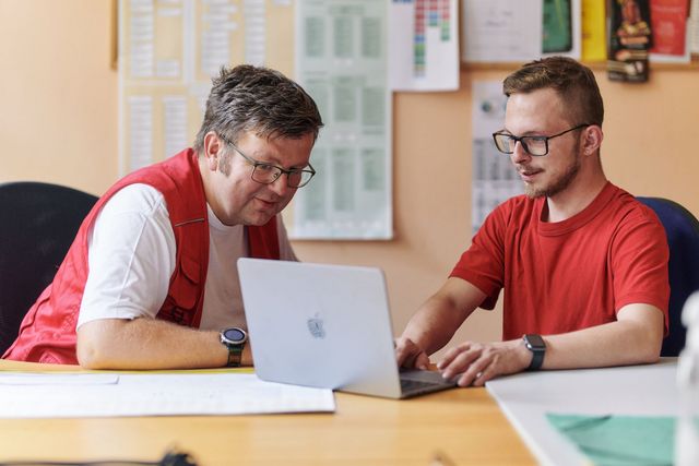 DRK-Mitarbeiter und junger Mann im Gespräch am Comuter.