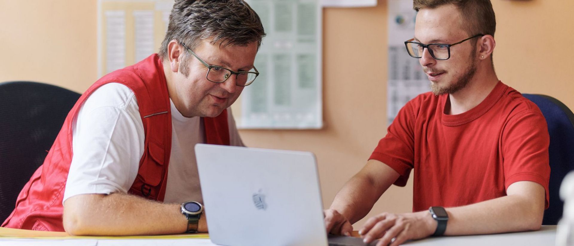 DRK Mitarbeiter und junger Mann im Gespräch am Computer.