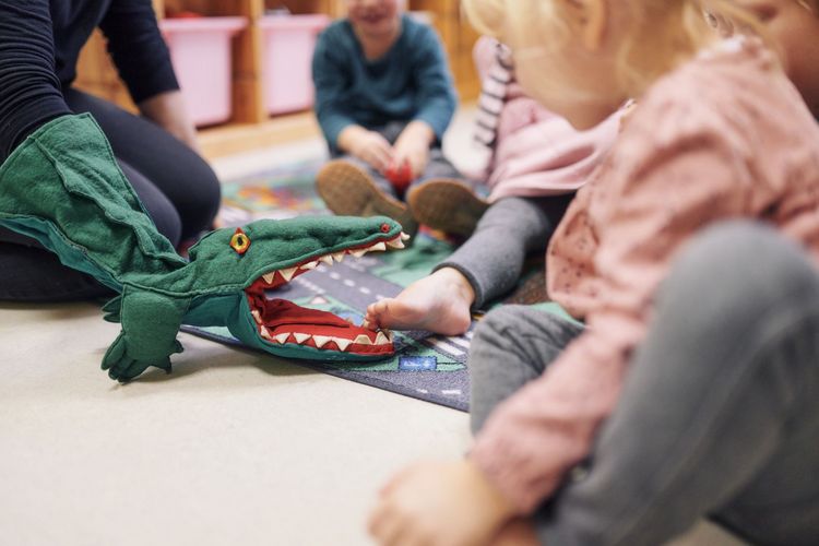 Handpuppe in Form eines Krokodils spielt mit den Kindern.