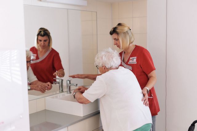 DRK Mitarbeiterin unterstützt Seniorin beim Händewaschen.