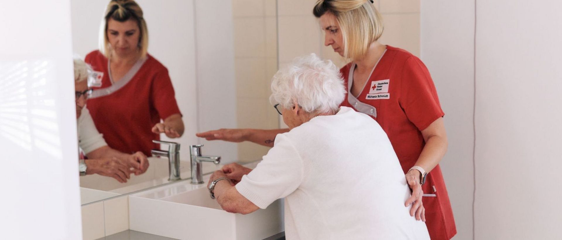 DRK Mitarbeiterin unterstützt Seniorin beim Händewaschen.