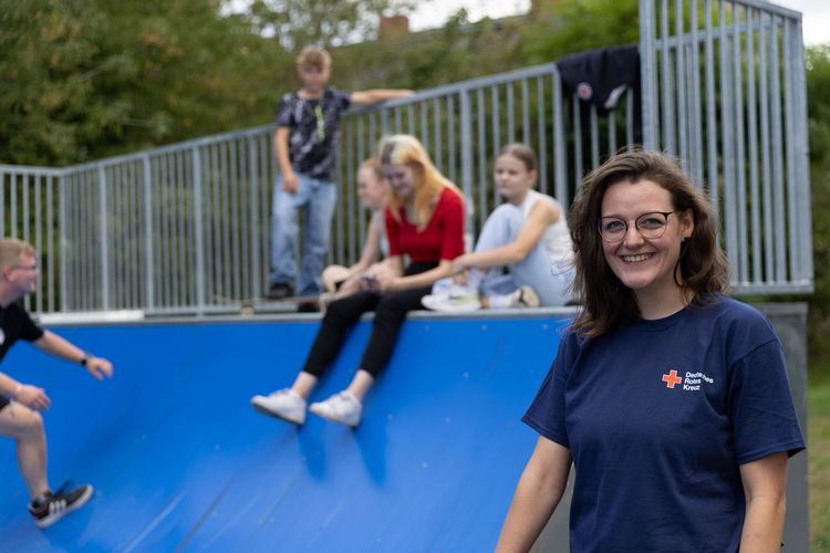 Jugendmitarbeiterin des DRK steht vor Halfpipe mit Jugendlichen.