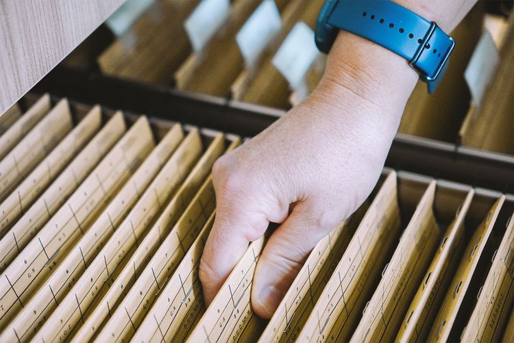 Hand greift Akte aus Schrank.