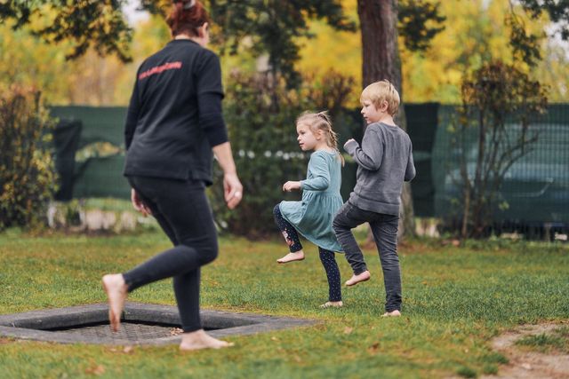 Erzieherin und Kinder laufen barfuß durch den Garten.