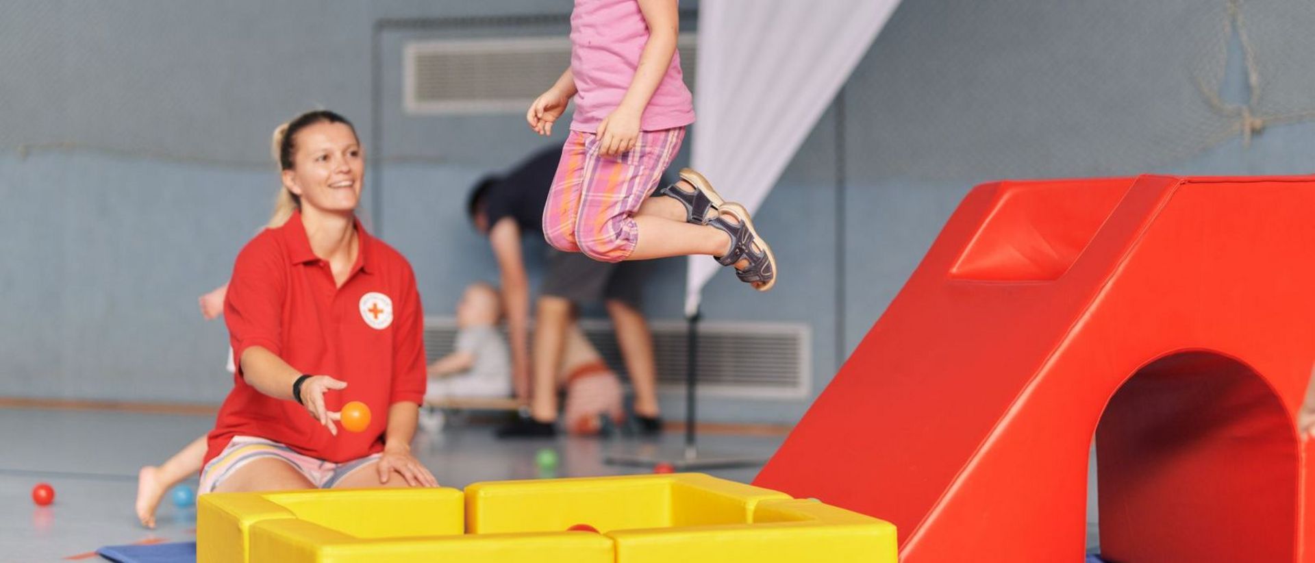 DRK-Mitarbeiterin beim Kinderturnen als Anleiterin und Aufsichtsperson.