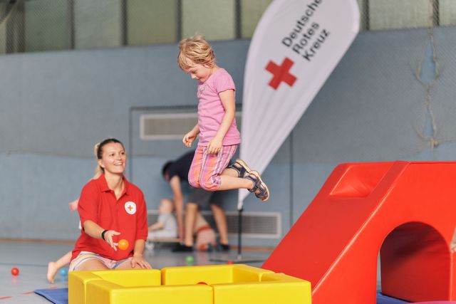 DRK-Mitarbeiterin beim Kinderturnen als Anleiterin und Aufsichtsperson.