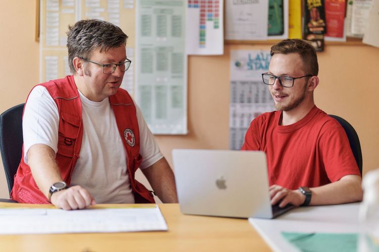 Junger Erwachsener und DRK Mitarbeiter im Beratungsgespräch.