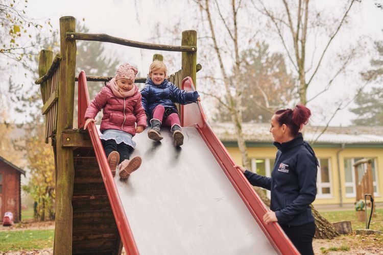 Erzieherin beaufsichtigt Kinder beim Rutschen.