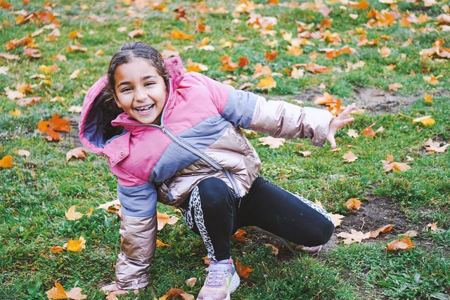 Ein fröhliches Mädchen spielt im Gras.