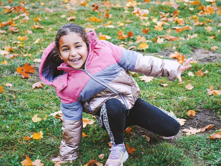 Auf diesem Bild sieht man ein Mädchen aus unserer Besonderen Wohnform Mozartkids, welches glücklich lächelnd im Garten turnt.