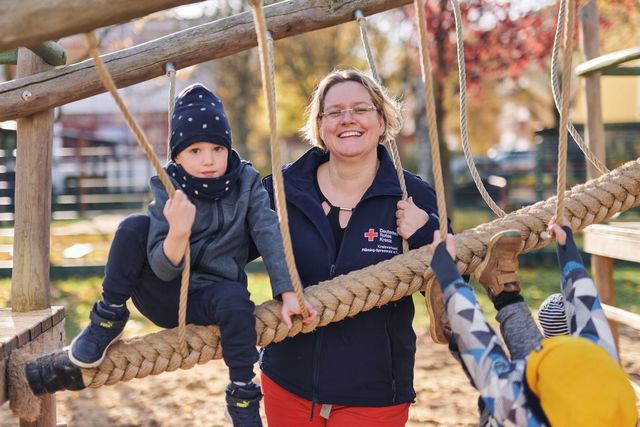 Erzieherin und Kind lachen in die Kamera.