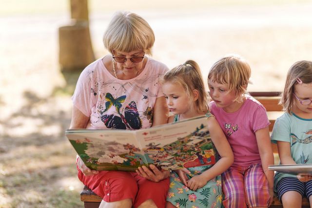Seniorin liest mit Kindern ein Buch.