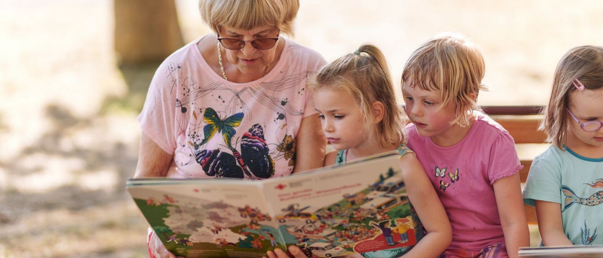 Seniorin liest mit Kindern ein Buch.