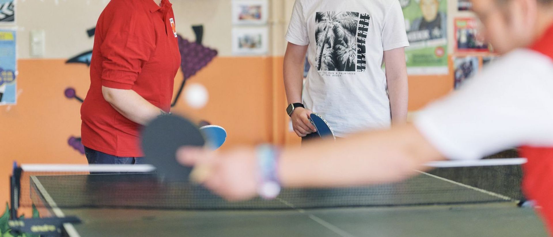 3 Personen spielen Tischtennis.