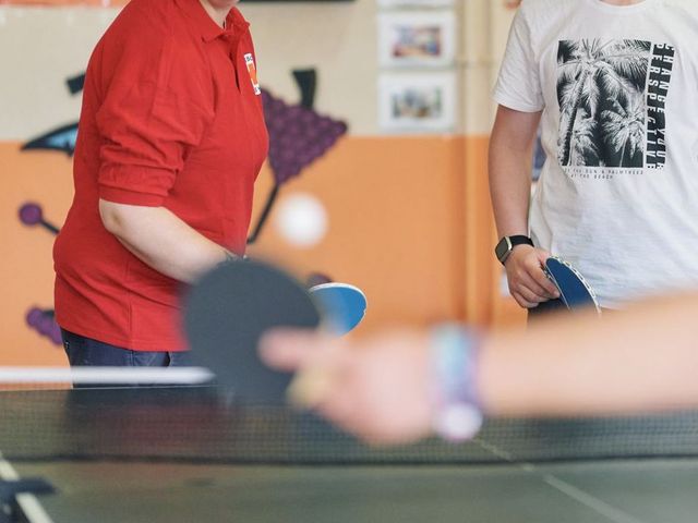 3 Personen spielen Tischtennis.