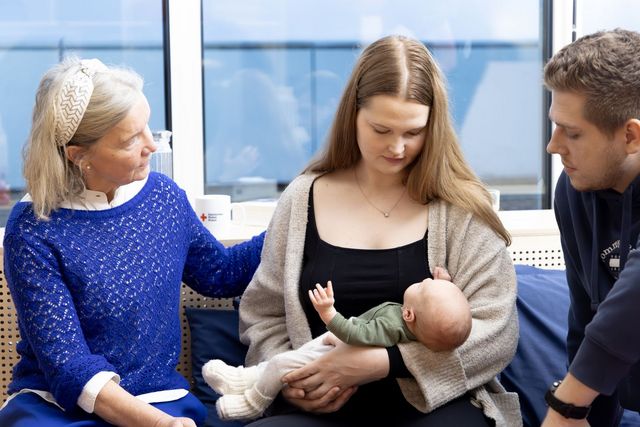 Beraterin und junge Frau, die ihr Baby in den Armen hält.