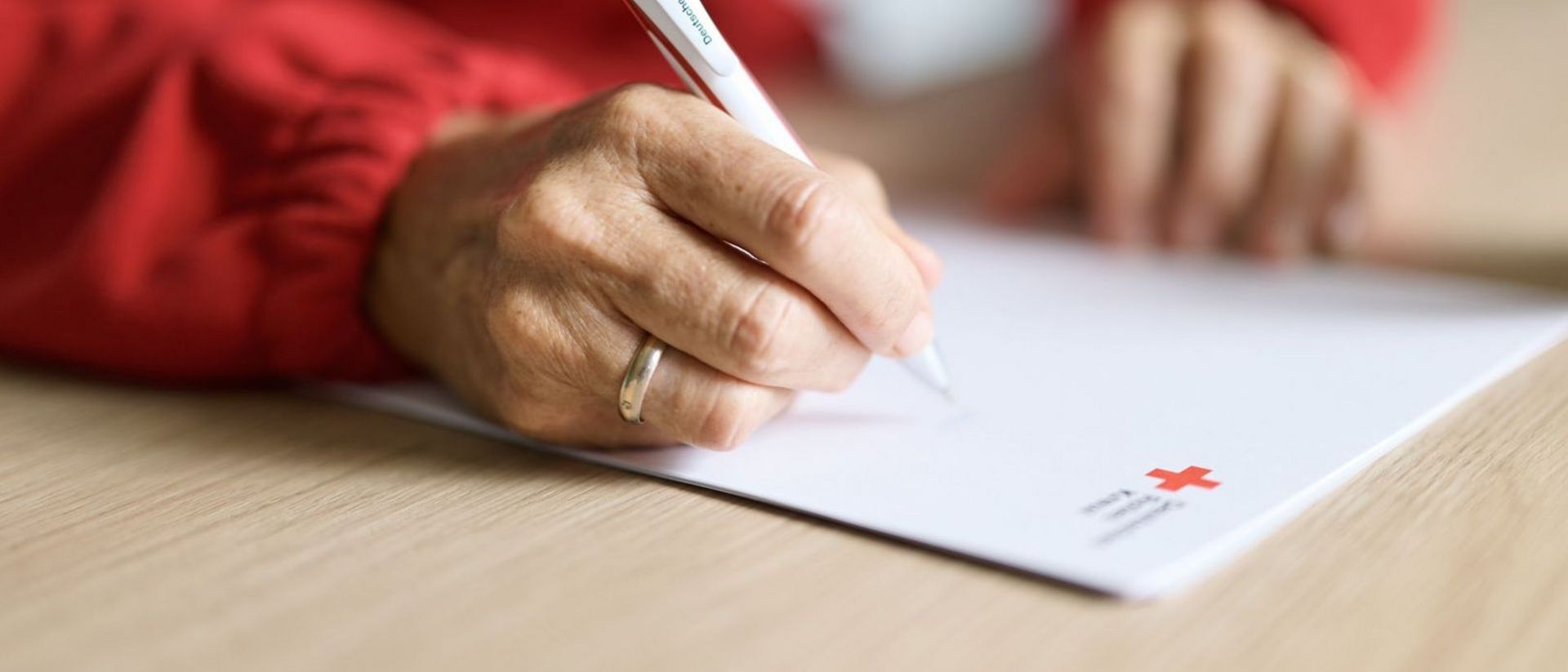 Man sieht in dem Symbolbild eine Hand, welche einen Stift führt, als würde Sie auf einem Blatt Papier etwas schreiben.