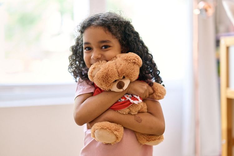 Mädchen kuschelt mit Teddybär.