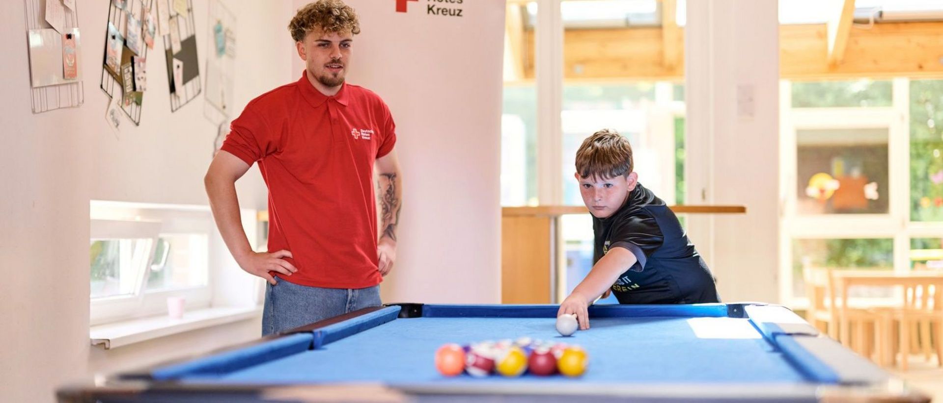 DRK Mitarbeiter und Junge spielen Billard